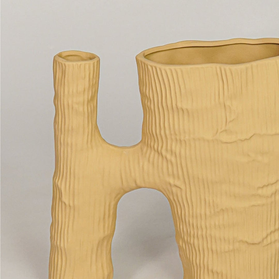 Closeup of beige ceramic vase with textured wood inspired finish for artistic tabletop and shelf decor styling.