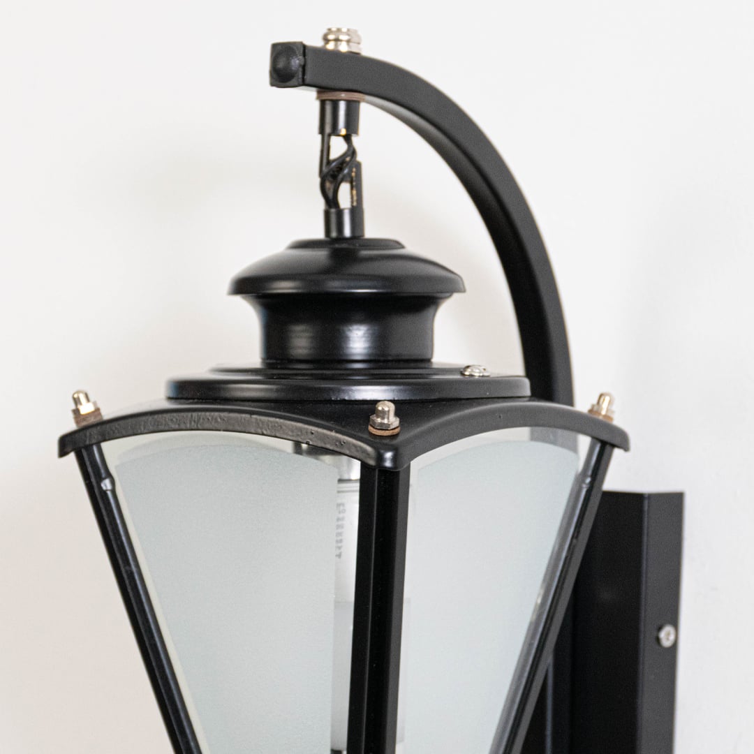 Closeup of black metal outdoor wall lantern with frosted glass panels showing textured finish sturdy build and classic detailing.