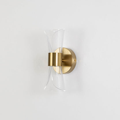 Gold wall light with sculpted clear glass shade shown on a bright white background with lights off for clarity.