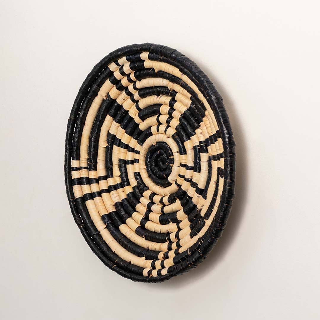 Side view of handcrafted black and cream woven seagrass wall basket with geometric maze pattern for bohemian wall decor.