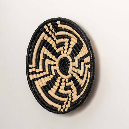 Side view of handcrafted black and cream woven seagrass wall basket with geometric maze pattern for bohemian wall decor.