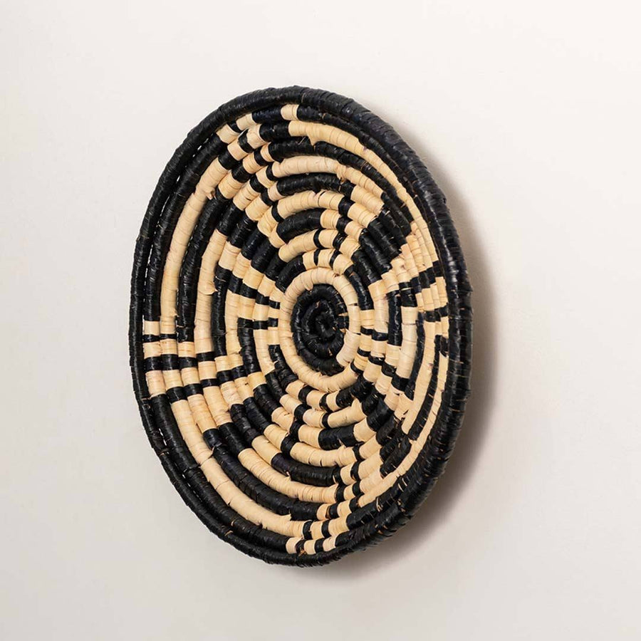Side view of handcrafted black and cream woven seagrass wall basket with geometric maze pattern for bohemian wall decor.