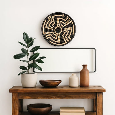 Medium black and beige woven wall basket hanging above a wooden console table with green rubber plant for modern home decor.