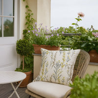 Soft cotton cushion cover with green floral embroidery styled on an outdoor chair adding a fresh nature inspired décor touch with a breathable gentle and skin friendly fabric feel.