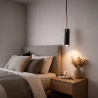 Black metal spotlight pendant light beside the bed creating warm ambiance with modern elegance indoors.