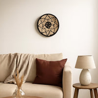 A handwoven natural and black rattan wall decor plate styled above a beige sofa with a brown cushion neutral throw and wooden side table creating warm cozy home vibes.