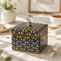 Black decorative storage box with gold geometric pattern styled on a coffee table for luxury modern home decor.
