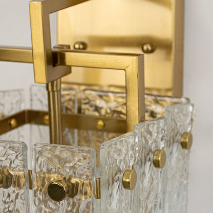 Closeup of luxury gold wall sconce with detailed textured glass shade and sturdy metal frame showing premium modern craftsmanship.
