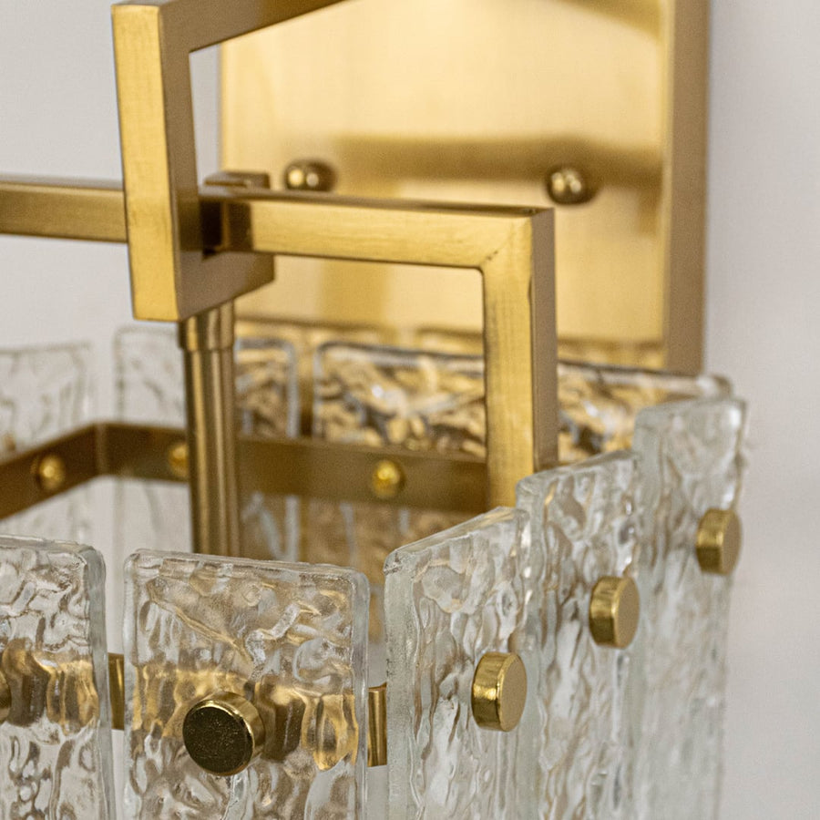 Closeup of luxury gold wall sconce with detailed textured glass shade and sturdy metal frame showing premium modern craftsmanship.