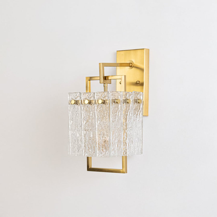 Minimalist gold wall sconce with textured glass shade shown switched off against plain white background for product photography.