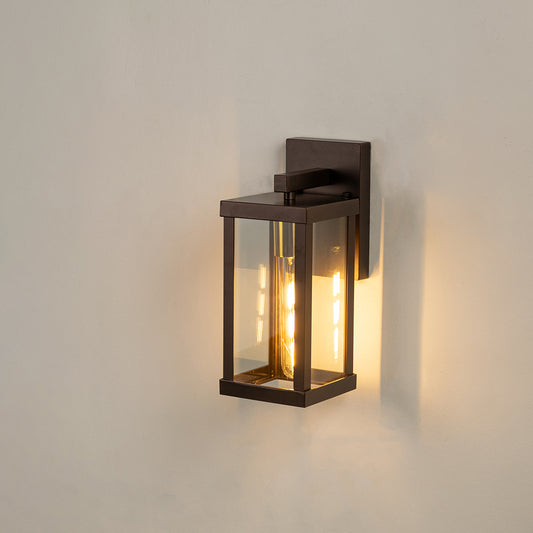 Modern black rectangular outdoor wall light on white background with clear glass panels casting a warm vintage bulb glow.
