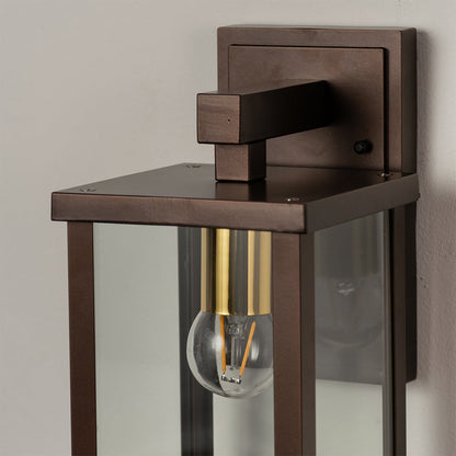 Closeup of metal wall lantern with clear glass detailing showing bulb design and refined outdoor lighting style.