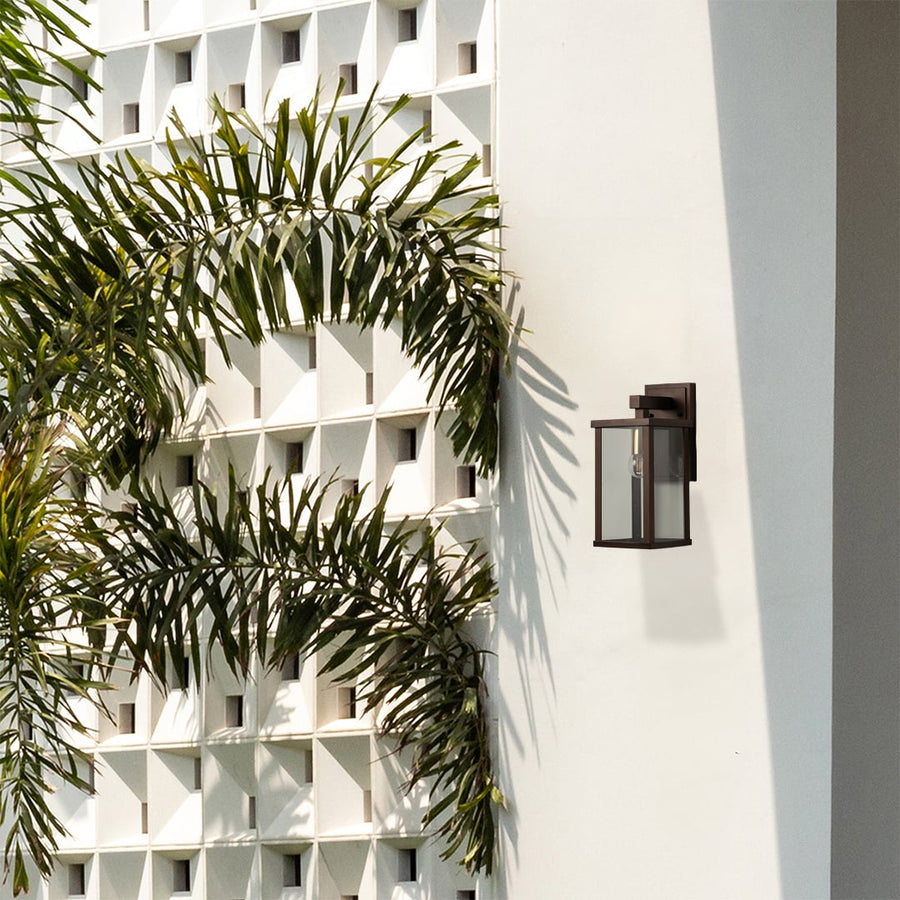 Elegant metal wall lantern with clear glass panels creating warm ambient outdoor lighting for entryways and patios.