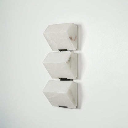 Modern white wall light with geometric cube design mounted on neutral wall background ideal for contemporary bedroom or hallway lighting.