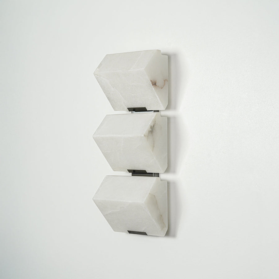 Modern white wall light with geometric cube design mounted on neutral wall background ideal for contemporary bedroom or hallway lighting.