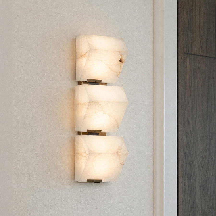 Artistic wall light with stacked sculptural glass shades mounted on neutral wall background ideal for modern decorative interior lighting.
