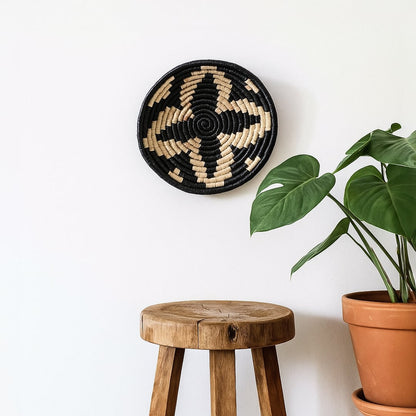 Round metal wall decor with abstract tribal inspired pattern displayed above wooden stool adding artistic contrast and handcrafted charm to modern interiors.