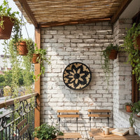 Decorative round wall clock with nature inspired motif mounted on rustic brick wall enhancing outdoor patio decor with earthy texture and visual warmth.