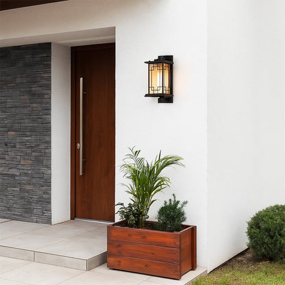 Gold outdoor wall lantern with the light on mounted beside a wooden entrance door creating a warm welcoming glow for modern exterior home decor styling.