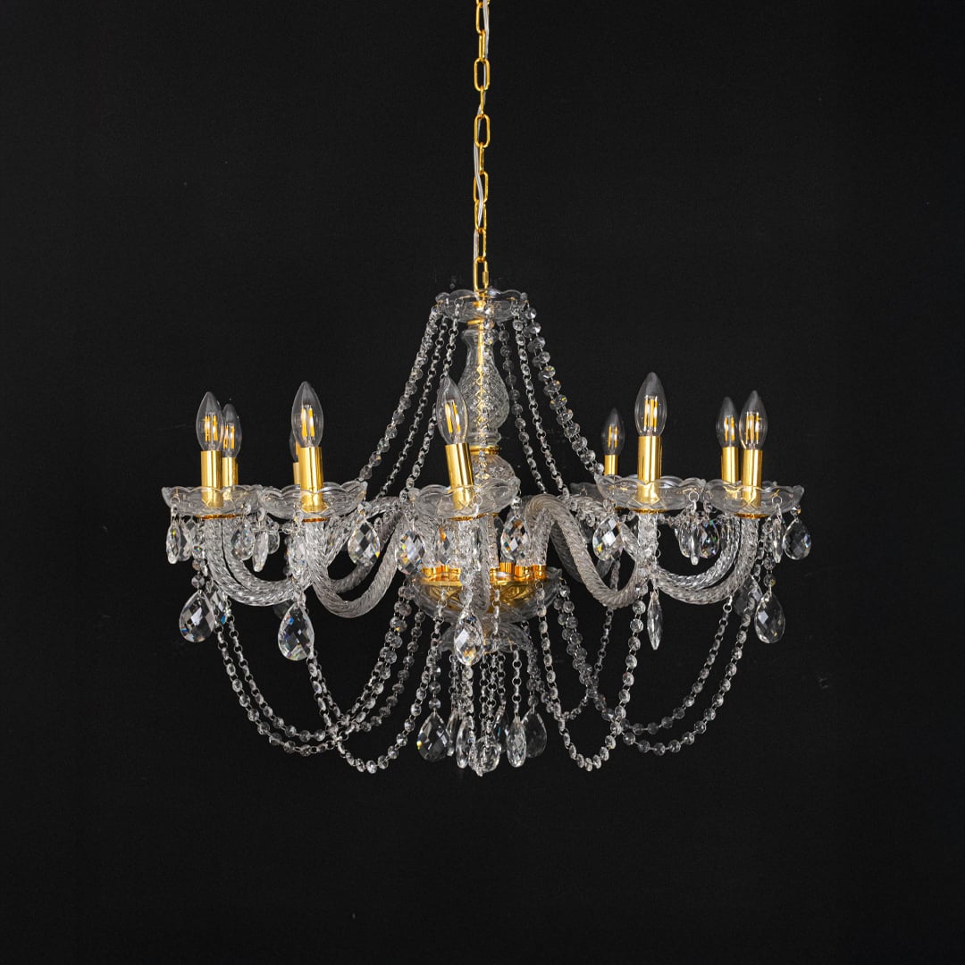 Chandelier with gold detailing and crystal accents displayed off against black background for decor style.