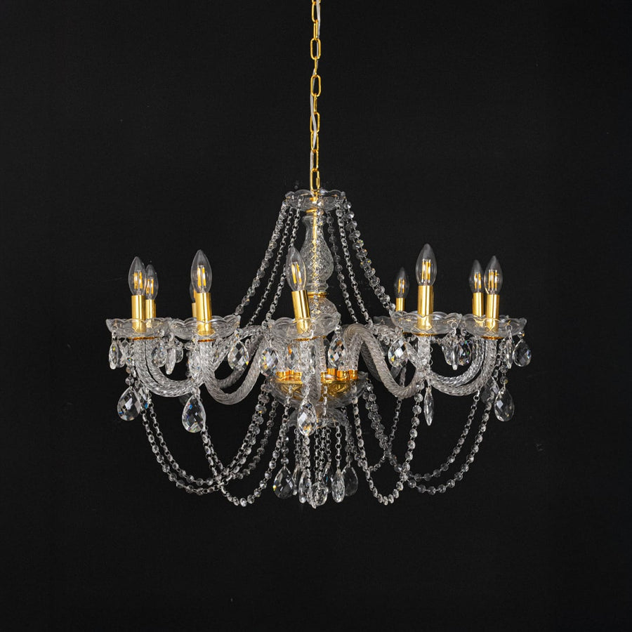 Chandelier with gold detailing and crystal accents displayed off against black background for decor style.