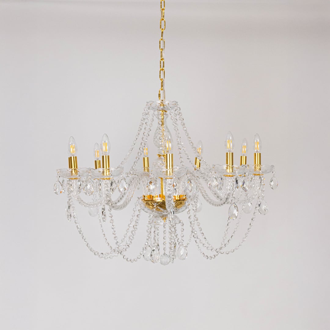 Classic chandelier with crystal and gold finish shown off on white background for modern home decoration.