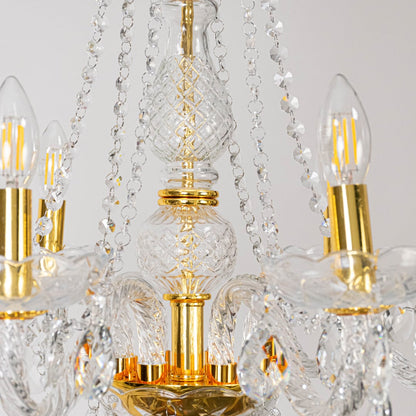 Closeup of chandelier with crystal arms and gold finish showing intricate glass details and light design.