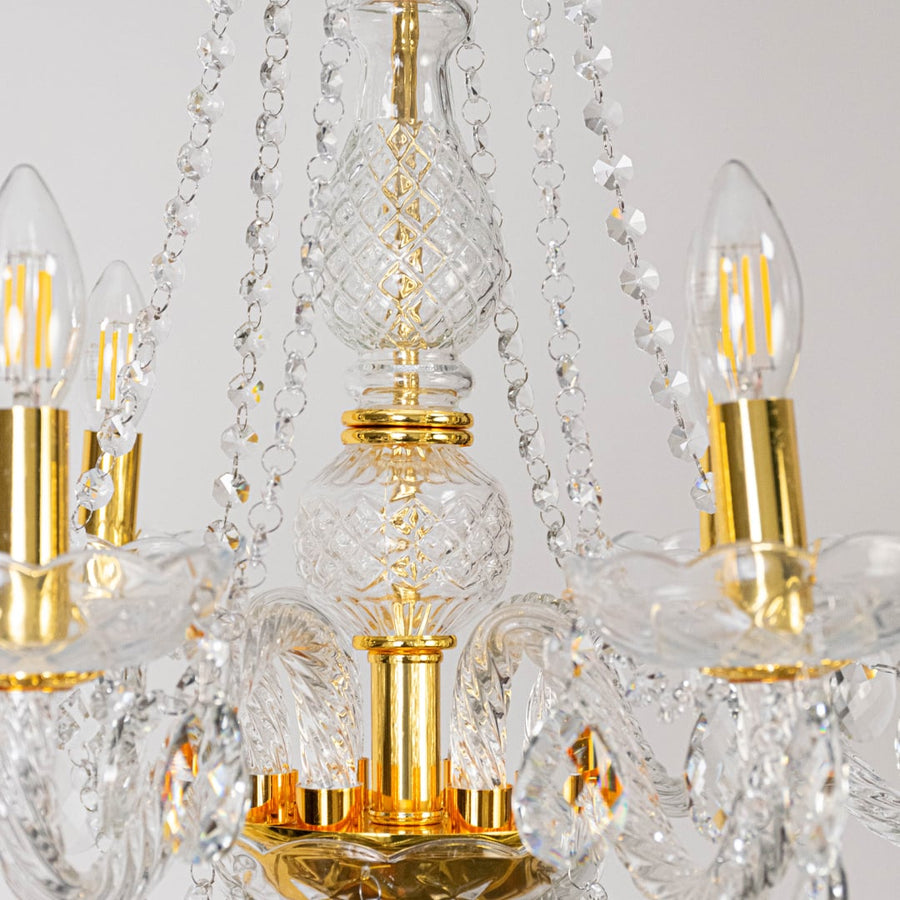 Closeup of chandelier with crystal arms and gold finish showing intricate glass details and light design.