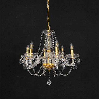 Chandelier with gold base and crystal design turned off against black background for modern interior styling.