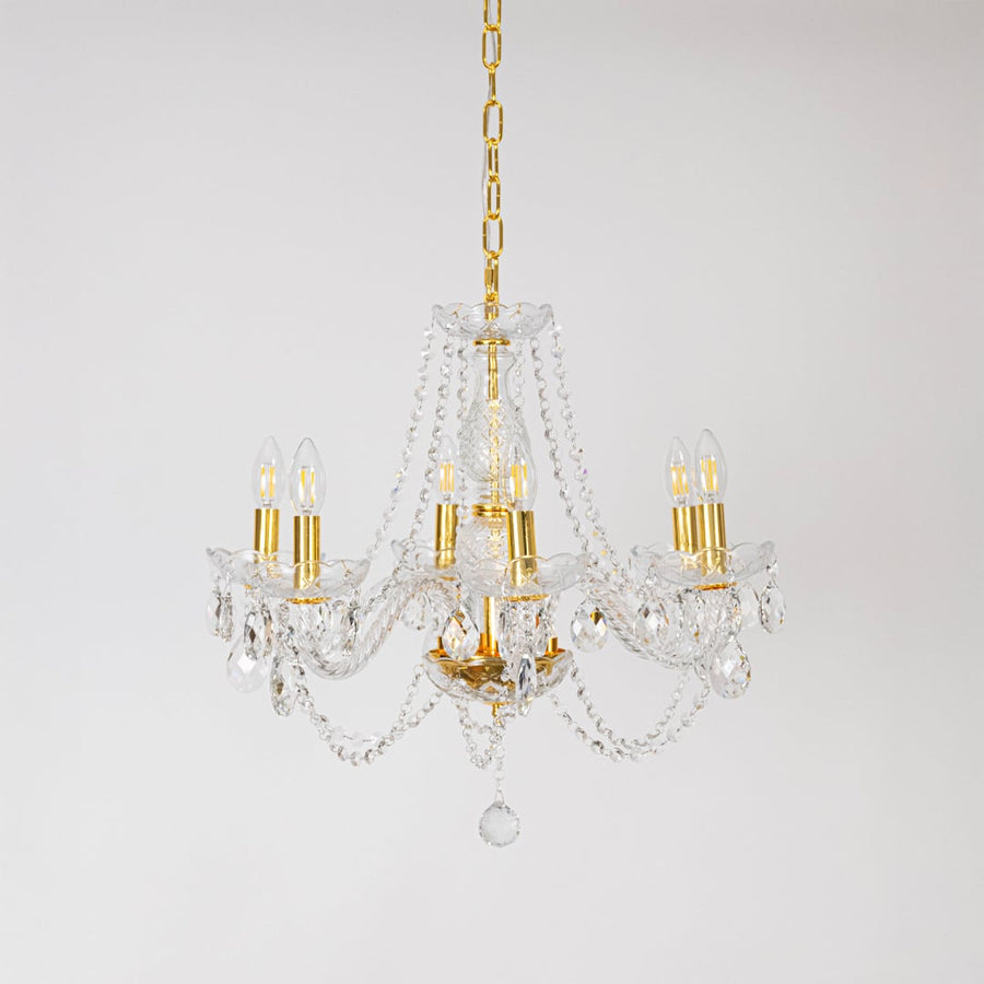 Classic chandelier with crystal and gold finish displayed off on white background for decorative lighting.