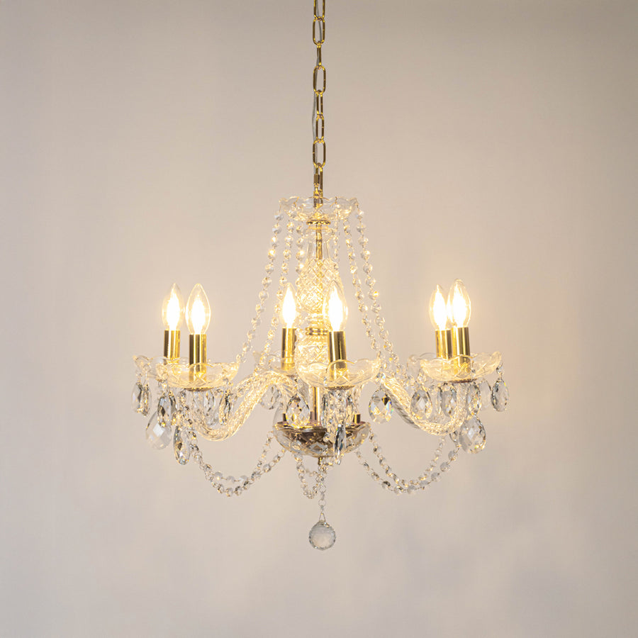 Clear crystal chandelier with illuminated candle bulbs and sparkling crystal drops creating luxurious traditional ceiling lighting.