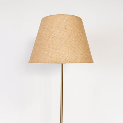 Closeup of floor lamp with beige linen lampshade and golden metallic stand showing premium texture.