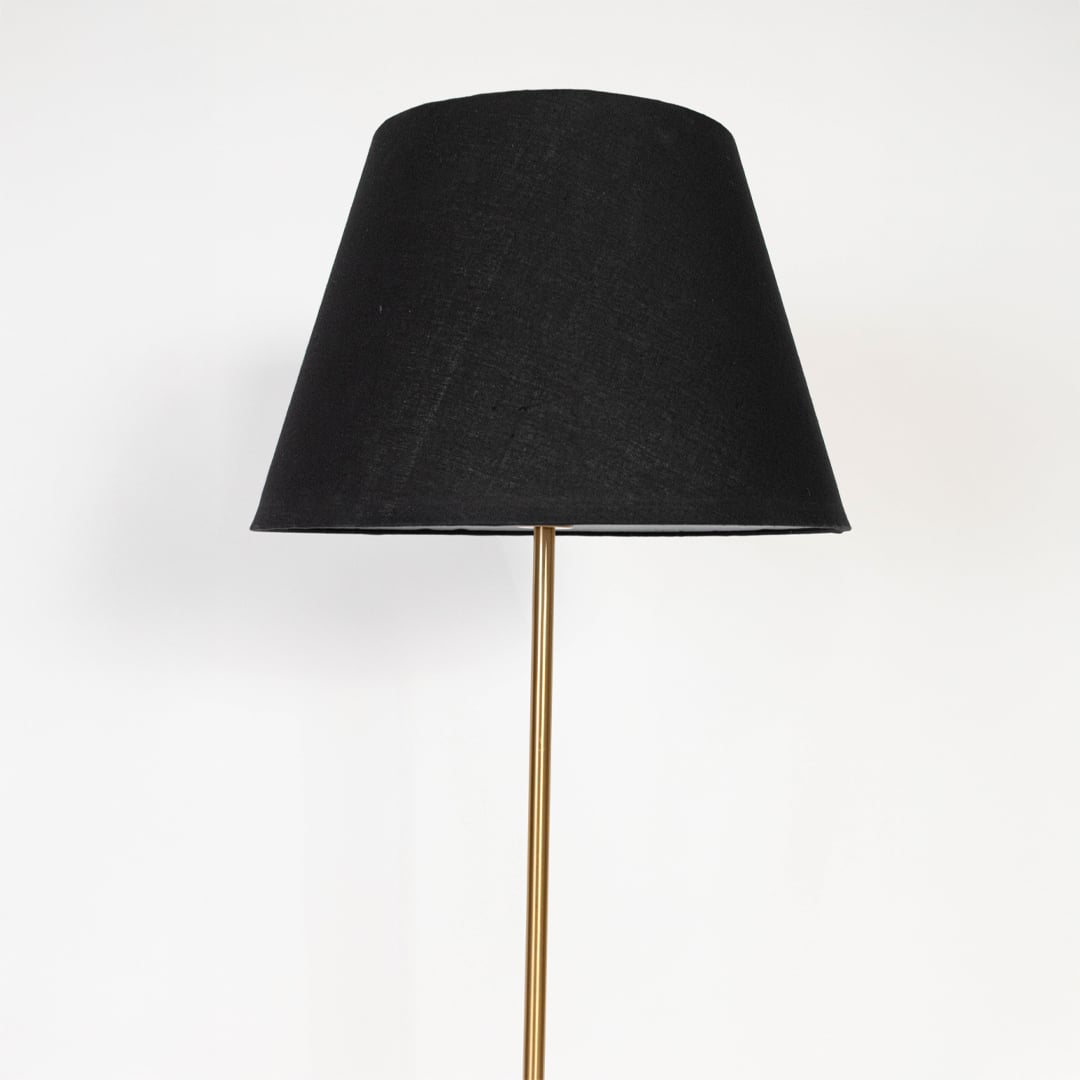 Closeup of floor lamp with black tapered shade and golden stand highlighting luxurious finish.