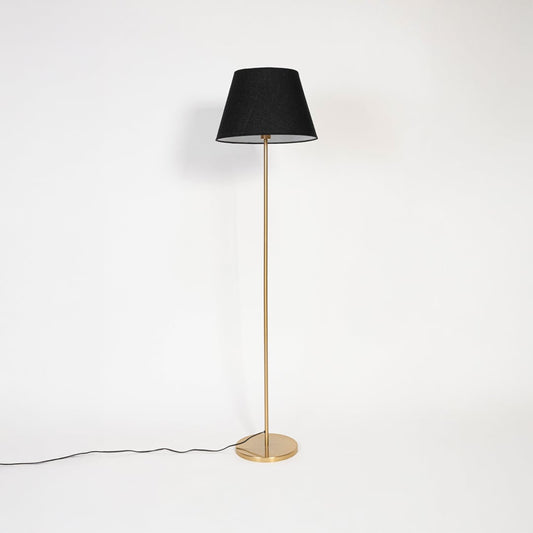 Floor lamp with black lampshade and golden base switched off on plain white background.