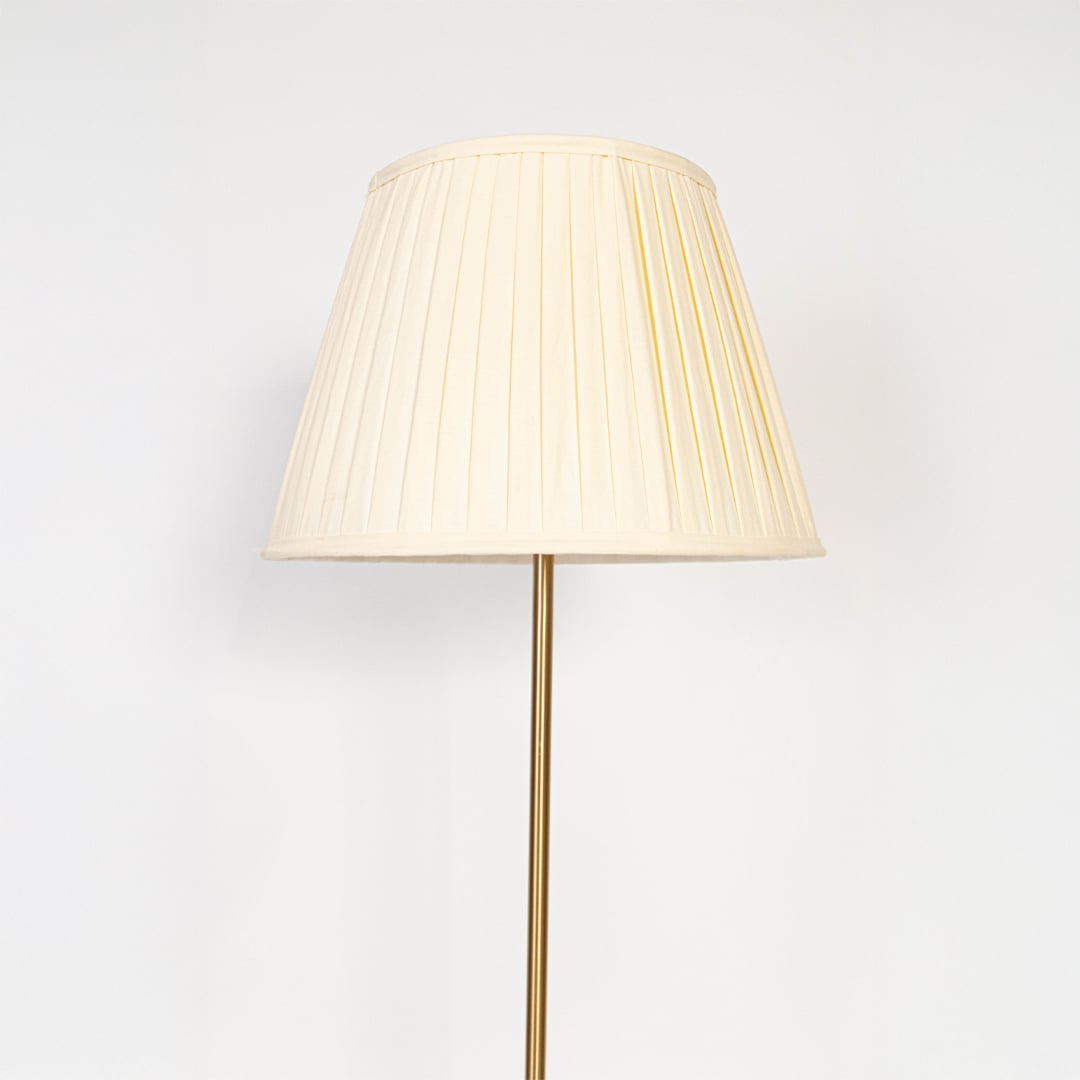 Closeup of golden floor lamp with pleated shade highlighting slim stand and premium modern lighting design.
