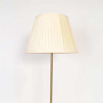Closeup of golden floor lamp with pleated shade highlighting slim stand and premium modern lighting design.