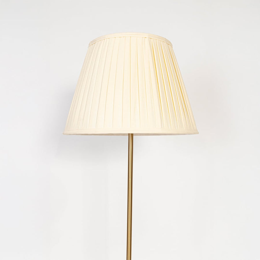 Closeup of golden floor lamp with pleated shade highlighting slim stand and premium modern lighting design.