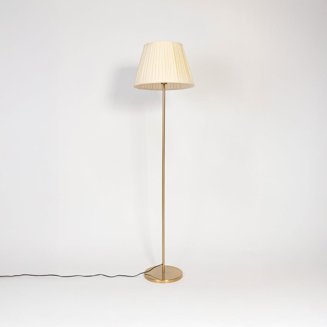 Golden floor lamp with pleated white fabric shade displayed turned off on plain white background.