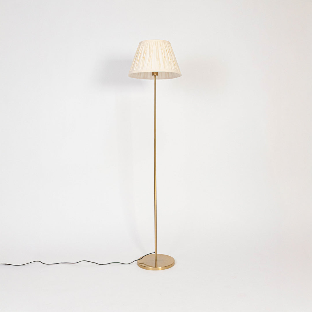 Floor lamp with white pleated fabric shade and golden stand displayed on white background with light off.