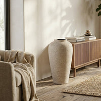 Beige textured floor vase placed beside cabinet for elegant modern living room decor styling.