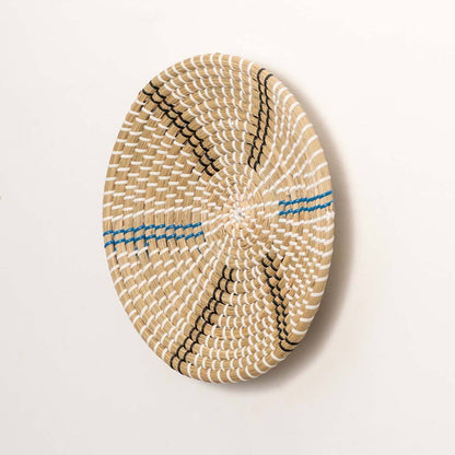 Side view of handcrafted natural cream seagrass wall basket with blue and grey striped spokes for boho wall decor display.