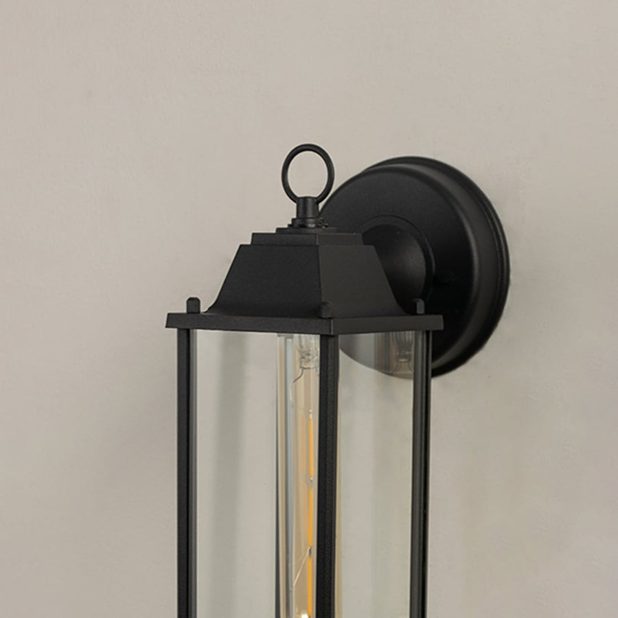 Close view of the black outdoor lantern highlighting the clear glass panels and elongated bulb inside.