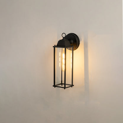 Minimalist black elongated outdoor wall light on white background with clear glass panels casting a warm downlight glow.