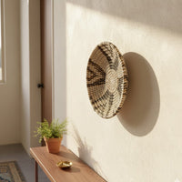Handwoven wicker wall plate in natural brown with black and white weaving lifestyle image perfect for stylish wall decoration.