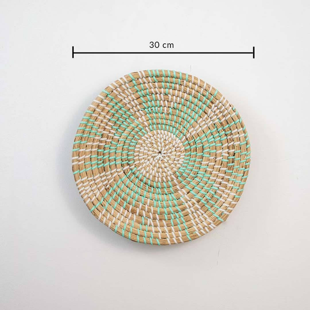 Handwoven seagrass round wall basket decor in natural beige and mint with spiral woven pattern and size guide on white.