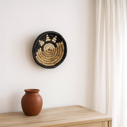 Decorative round wall clock with botanical leaf design in earthy finish displayed on shelf creating warm handcrafted appeal for modern home decor styling.