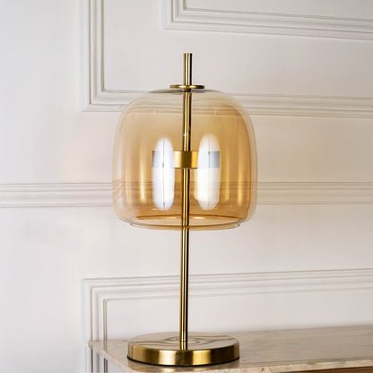 Gold metal table lamp with amber glass shade shown switched off on white background for minimal stylish decor.