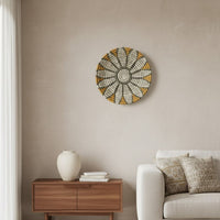 Circular wall decor in soft neutral and gold tones mounted above wooden console adding elegant focal point to calm modern living space.