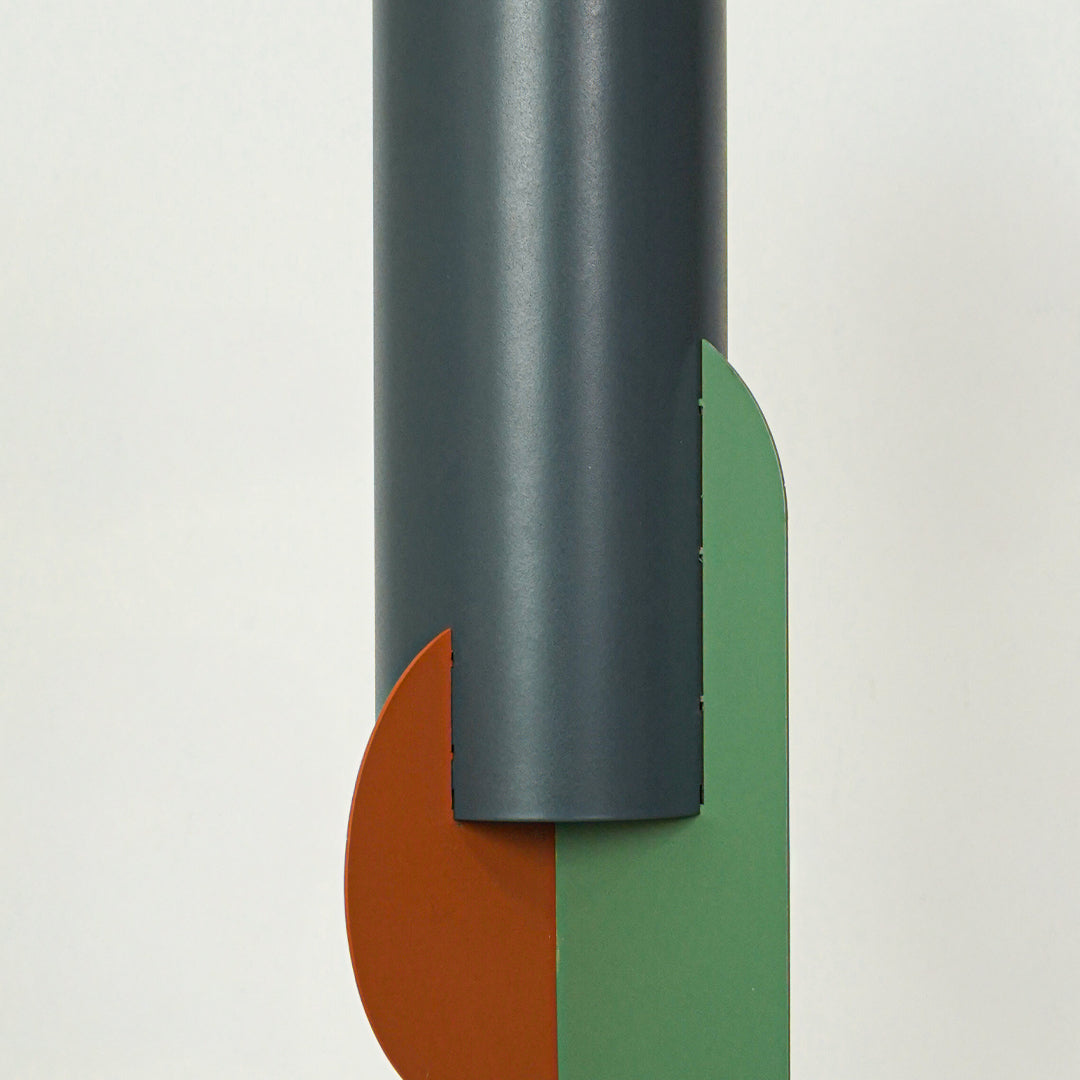 Closeup of charcoal metal pendant light highlighting orange and green glass accents and craftsmanship.