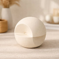 Minimal cream ceramic sphere decor object placed on tabletop in warm neutral living room setting for modern home styling.
